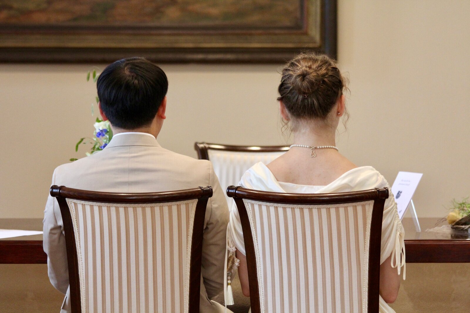 Yongjai and Vanessa seated side by side during the ceremony, seen from behind